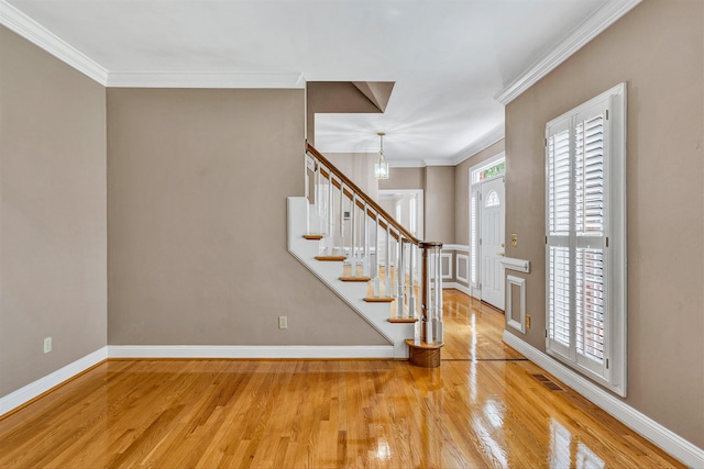 entryway with crown molding, stairs, and wood finished floors