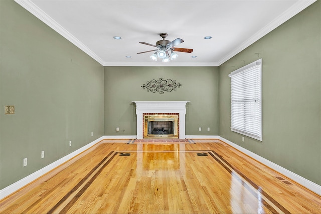 unfurnished living room featuring crown molding, a brick fireplace, wood finished floors, and baseboards