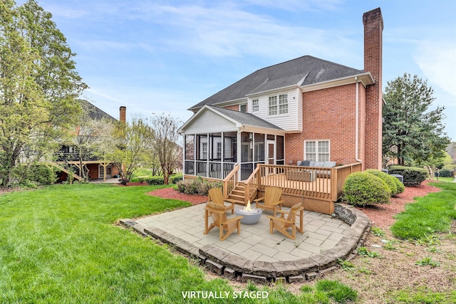 rear view of house with a patio, a chimney, a lawn, an outdoor fire pit, and a sunroom