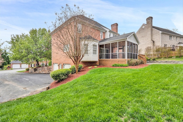 exterior space featuring a garage, a sunroom, a chimney, fence, and a front lawn