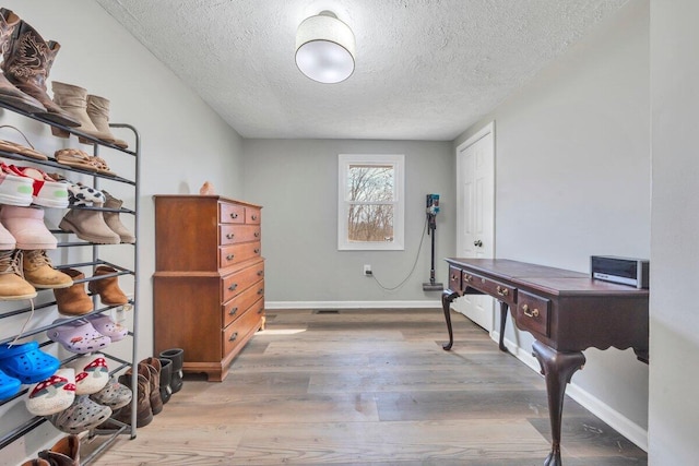 interior space featuring a textured ceiling, baseboards, and wood finished floors