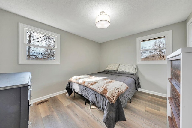 bedroom featuring baseboards, visible vents, and light wood finished floors