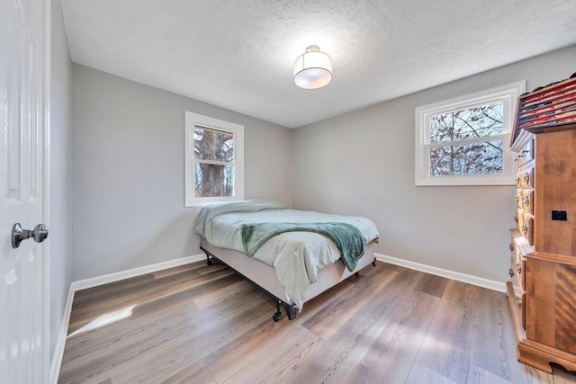 bedroom featuring multiple windows, baseboards, and wood finished floors