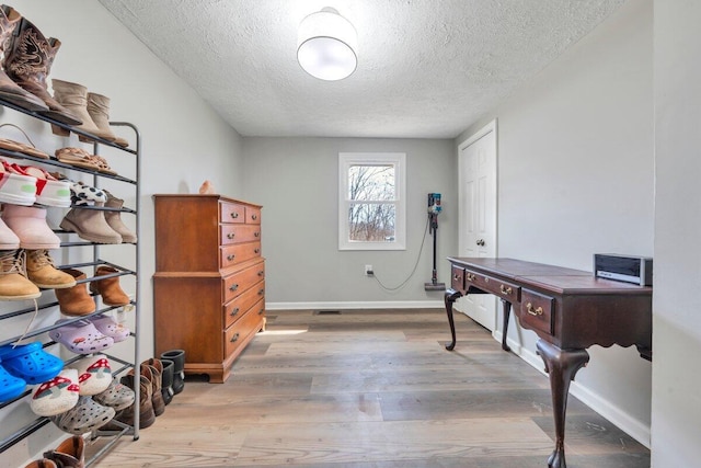 office area with a textured ceiling, baseboards, and wood finished floors