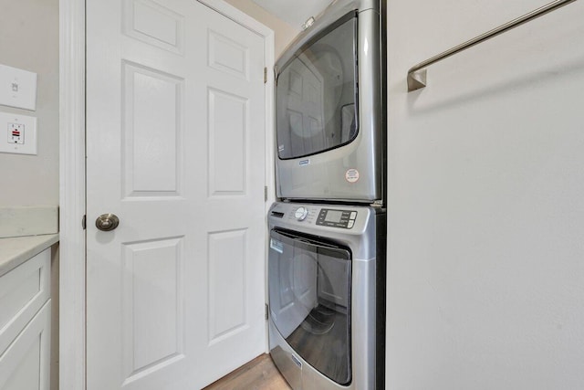 laundry area with light wood finished floors and stacked washer / drying machine