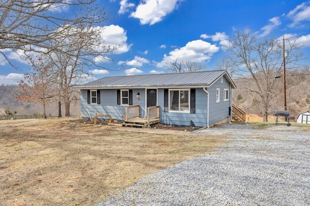 view of front of home featuring an outbuilding, gravel driveway, metal roof, and a storage unit