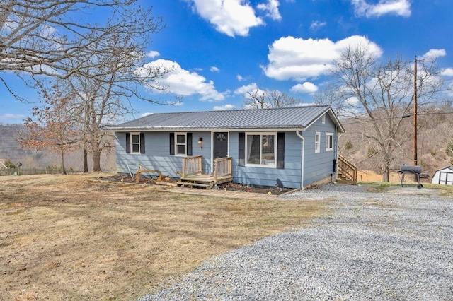 view of front of property with metal roof, a front lawn, and gravel driveway