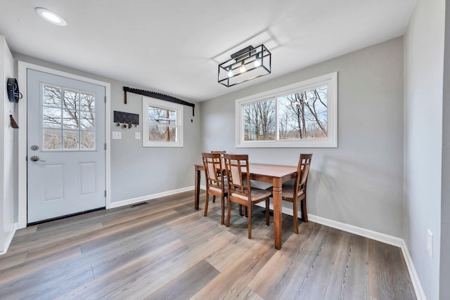 dining space featuring wood finished floors, visible vents, and baseboards