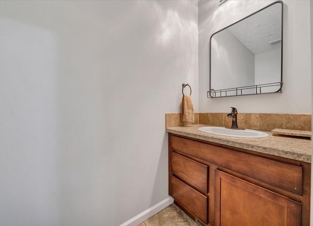 bathroom featuring visible vents, a textured ceiling, vanity, and baseboards