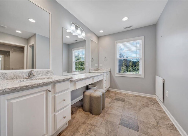 bathroom featuring baseboards, visible vents, radiator heating unit, vanity, and recessed lighting