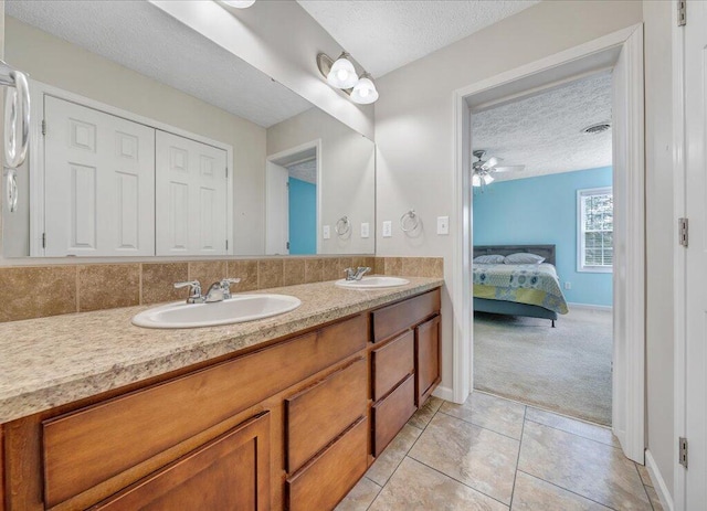 ensuite bathroom featuring a textured ceiling, ensuite bath, tile patterned flooring, and a sink