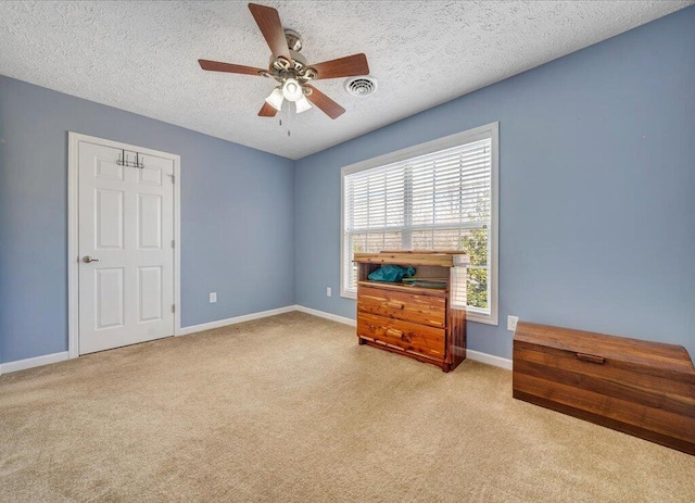 carpeted bedroom with a ceiling fan, visible vents, a textured ceiling, and baseboards