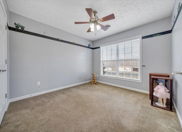 carpeted spare room featuring a ceiling fan, baseboards, and a textured ceiling