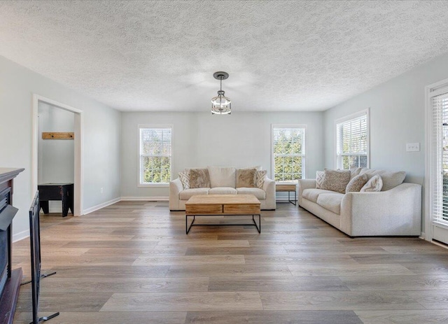 living area with plenty of natural light, a textured ceiling, baseboards, and wood finished floors