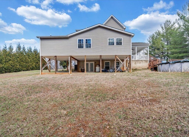 back of property featuring french doors, a covered pool, a yard, and stairway