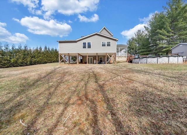 rear view of house with a yard, stairway, driveway, and a covered pool