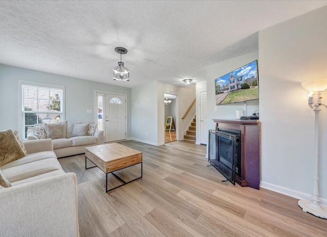 living room with a textured ceiling, stairway, a fireplace, and light wood-style floors