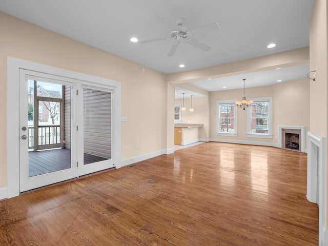 unfurnished living room featuring a fireplace, ceiling fan with notable chandelier, recessed lighting, and wood finished floors