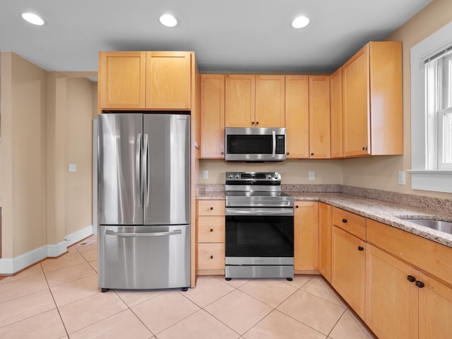 kitchen with light tile patterned floors, appliances with stainless steel finishes, and light brown cabinetry