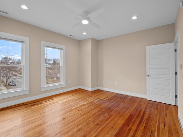 spare room featuring plenty of natural light, baseboards, light wood-style floors, and visible vents