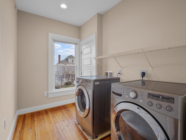 laundry room with light wood-type flooring, baseboards, separate washer and dryer, and laundry area