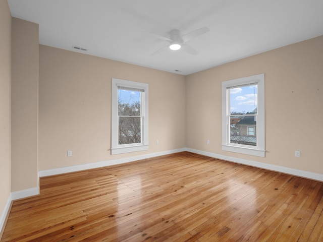 empty room featuring visible vents, baseboards, light wood-style floors, and a healthy amount of sunlight