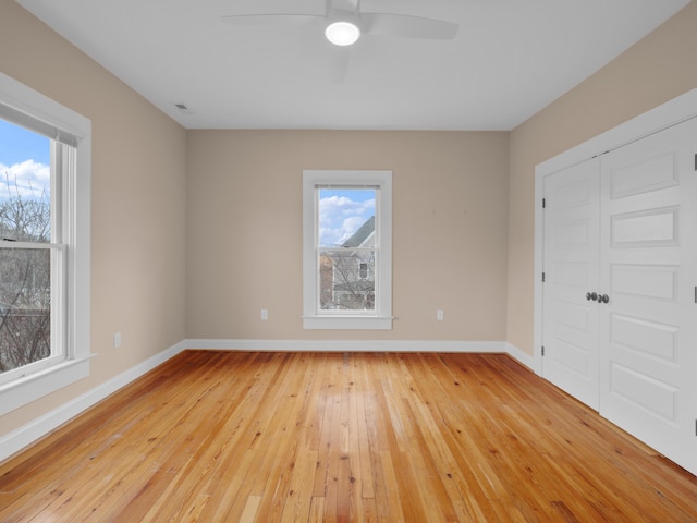 empty room featuring visible vents, a ceiling fan, baseboards, and light wood finished floors