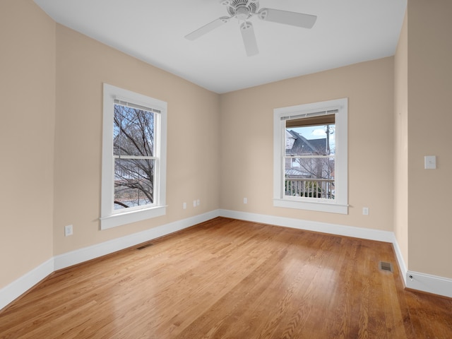 spare room featuring visible vents, baseboards, and wood finished floors