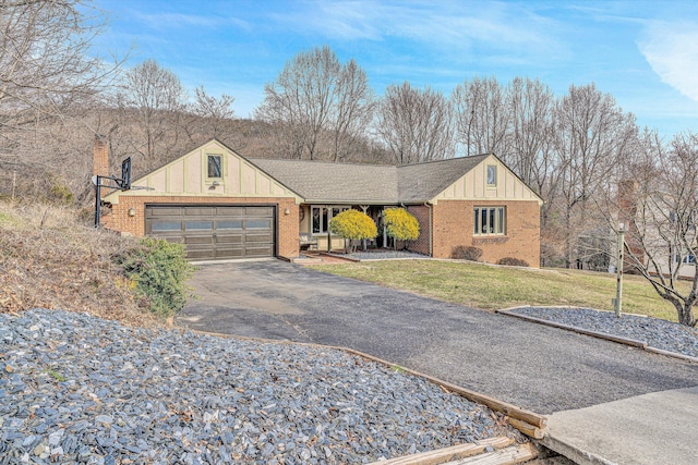 view of front facade featuring brick siding, board and batten siding, a front lawn, a garage, and driveway