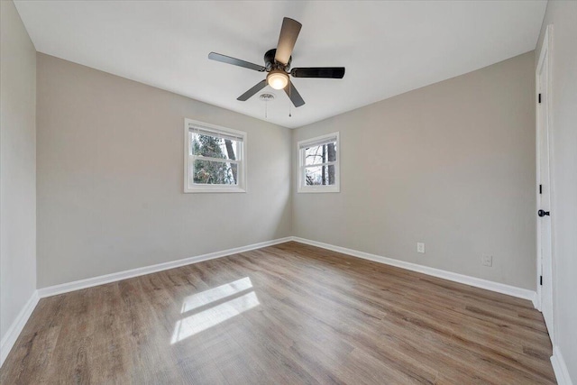 spare room featuring a ceiling fan, baseboards, and wood finished floors