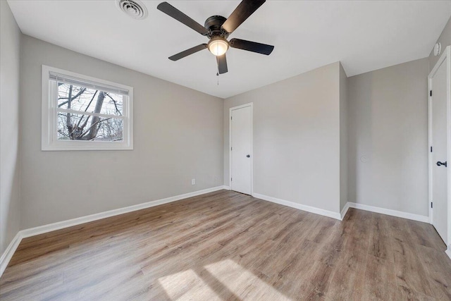 empty room featuring visible vents, baseboards, wood finished floors, and a ceiling fan