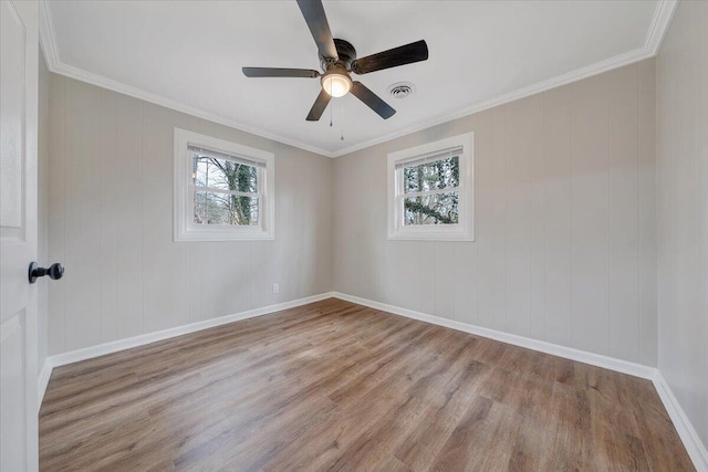 unfurnished room with wood finished floors, a healthy amount of sunlight, visible vents, and baseboards