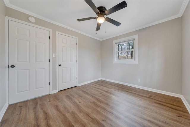 unfurnished bedroom featuring ceiling fan, crown molding, baseboards, and wood finished floors