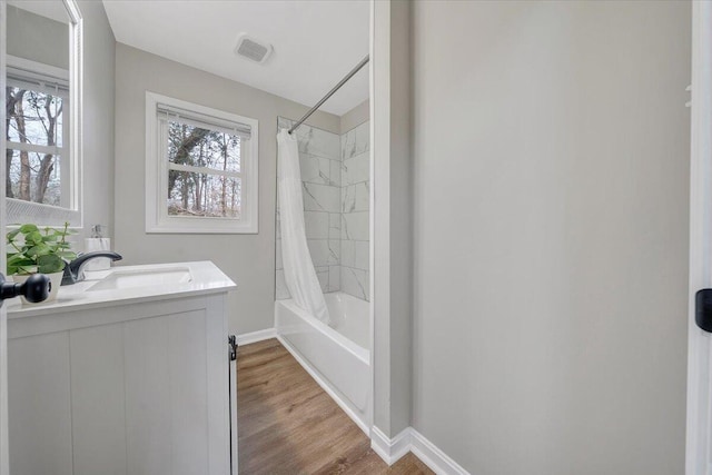 full bathroom featuring visible vents, shower / bath combo, wood finished floors, baseboards, and vanity