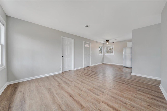 unfurnished living room with a ceiling fan, visible vents, baseboards, and light wood-type flooring