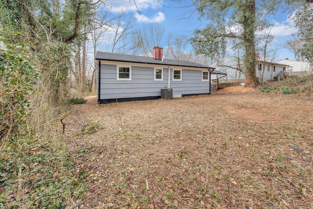 rear view of property featuring central air condition unit and a chimney