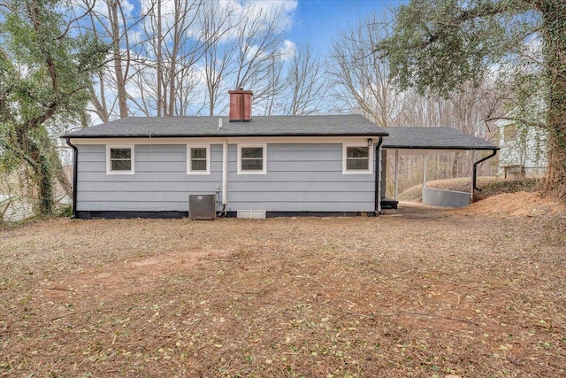 rear view of property with an attached carport, cooling unit, and a chimney