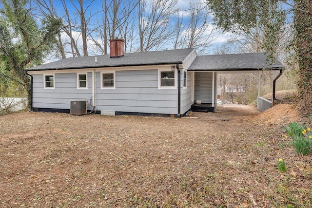 back of property featuring roof with shingles, central AC unit, and a chimney