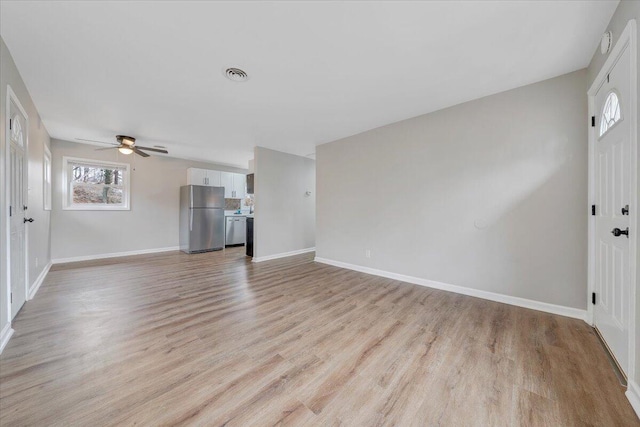 unfurnished living room with visible vents, a ceiling fan, light wood-type flooring, and baseboards