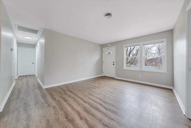 interior space with wood finished floors, baseboards, and visible vents