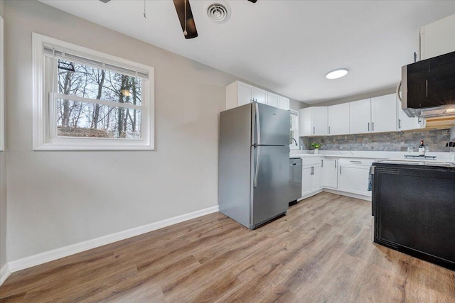 kitchen with tasteful backsplash, visible vents, light countertops, white cabinets, and stainless steel appliances