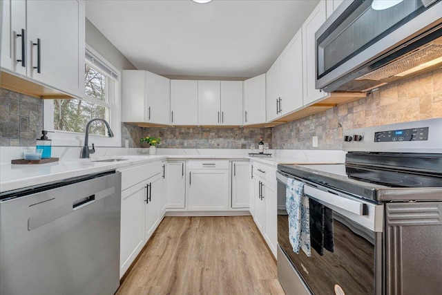 kitchen with white cabinetry, light wood-style flooring, tasteful backsplash, and stainless steel appliances