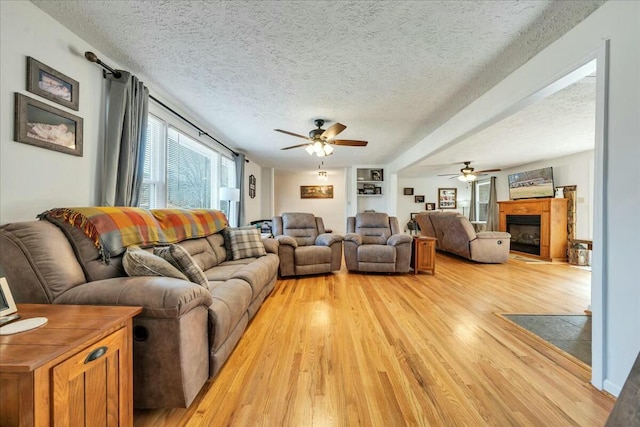 living area with a textured ceiling, light wood finished floors, and a fireplace