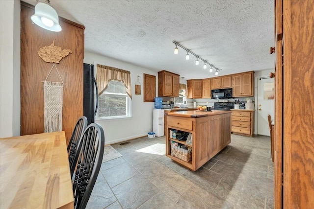 kitchen with butcher block countertops, a center island, a textured ceiling, black appliances, and track lighting