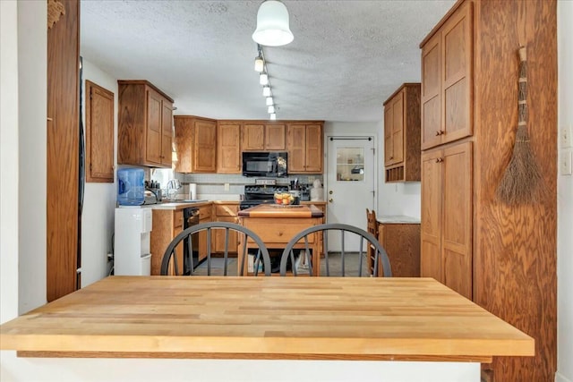 kitchen with a textured ceiling, black appliances, butcher block countertops, and brown cabinetry