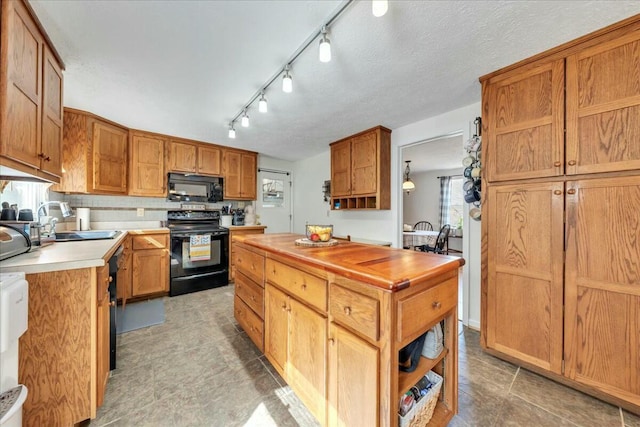 kitchen featuring butcher block counters, a sink, black appliances, open shelves, and backsplash