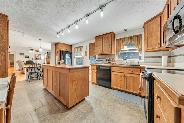 kitchen with tasteful backsplash, a kitchen island, brown cabinets, black appliances, and a sink