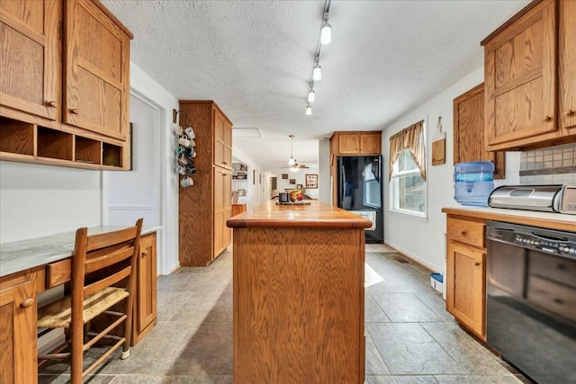 kitchen with a toaster, a kitchen island, light countertops, black appliances, and backsplash