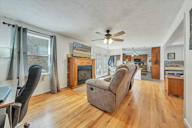 living room featuring a fireplace with raised hearth, a textured ceiling, and light wood finished floors