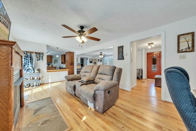 living room with light wood-style floors, baseboards, and a textured ceiling